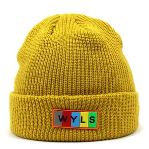 Close-up of ginger yellow ribbed knit beanie featuring a colorful WYLS letter patch