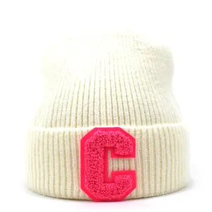 Detail of white ribbed knit beanie featuring a pink chenille letter C patch