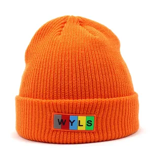 Close-up detail of the vibrant orange knit beanie showing texture and WYLS colorful label