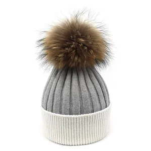 Bonnet en laine tricoté gris et blanc pour femme avec grand pompon en fourrure de raton laveur