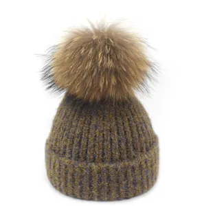 Detailopname van de meerkleurige gebreide muts met een grote pluizige bont pompon