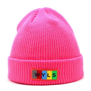 Close-up of bright pink knitted beanie featuring a colorful WYLS letter patch detail