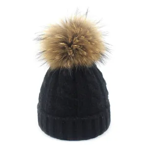 Detalle del gorro de punto negro con pompón de piel sintética y borde de canalé ancho
