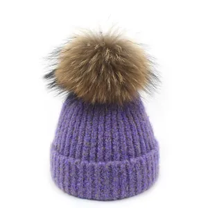 Detailtextuur van paarse gebreide muts met zachte pompon van imitatiebont voor winter