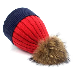 Bonnet en tricot rouge et bleu marine avec pompon en fausse fourrure sur fond blanc