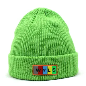 Detail of green ribbed knit beanie showing colorful rubber patch with WYLS lettering