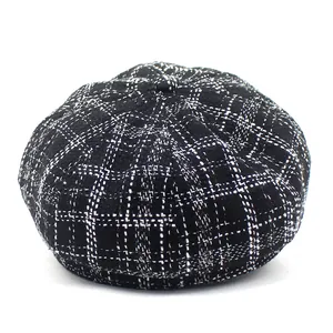 Detailed view of the woven plaid texture and top button on this vintage newsboy cap