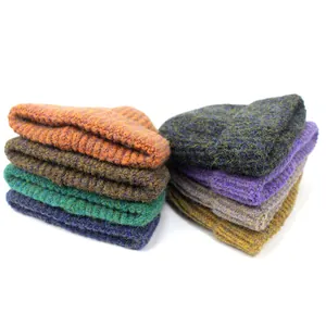 Stapel geribbelde gebreide mutsen met echt bont pompons in diverse warme kleuren