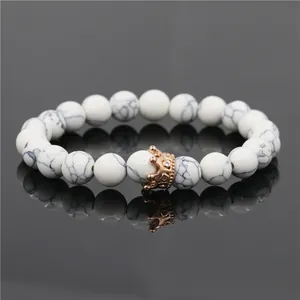 White turquoise bead bracelet with rose gold crown charm on mirror background