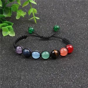 Macro detail of Seven Chakra braided bracelet with colorful natural stone beads on black background