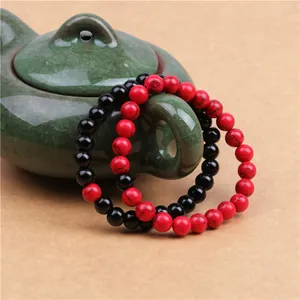 Dettaglio di bracciali in perline di turchese rosso e onice nera su un manico di teiera
