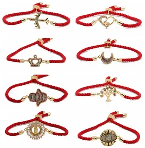 Detailed view of red braided bracelets with gold charms and colorful zircon stones