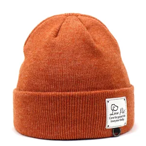 Detail van de gebreide oranje muts met Love Pet-label en metalen D-ring voor huisdieren