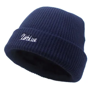 Détail du bonnet en maille côtelée bleu foncé avec broderie blanche XxYblue stylisée