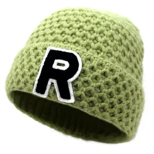 Detailed macro view of the avocado green knitted texture and embroidered R letter patch