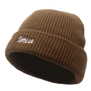 Détail d'un bonnet en maille marron avec broderie XyBlue blanche et texture côtelée
