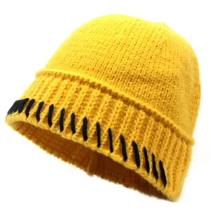 Nahaufnahme der gelben Strickmütze mit auffälligen schwarzen Kontrastnähten am Mützenrand