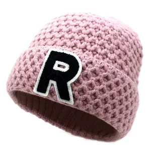 Detail of pink chunky knit beanie showing honeycomb texture and embroidered R patch