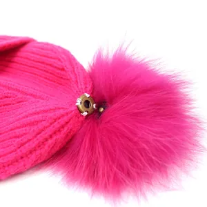 Dames gebreide muts in rozerood met een afneembare bontpompom en metalen drukknoopsluiting