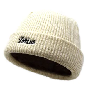 Gros plan sur un bonnet en maille crème avec broderie Skyblue noire et texture côtelée
