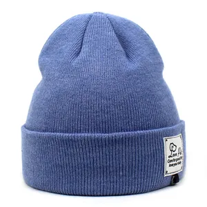 Detail van de blauwe geribbelde muts met decoratieve patch en een omgeslagen rand