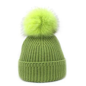 Detail van de gebreide textuur van de groene wintermuts met neon groene bontpompom