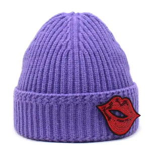 Detail der lila Strickmütze mit rotem Pailletten-Lippen-Patch am umgeschlagenen Rand