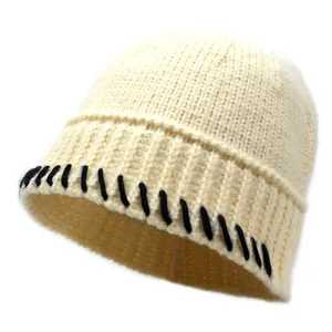 Detail der cremefarbenen Strickmütze mit Rippmuster und schwarzen Kontrastnähten am Saum