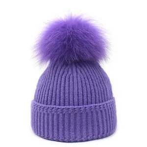 Detail van een paarse gebreide muts met een grote pompon van echt vossenbont bovenop