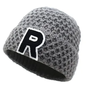 Detail of grey waffle knit beanie showing thick texture and embroidered R letter patch