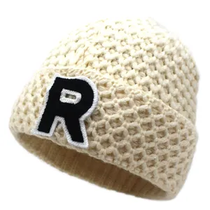 Creamy white cable knit beanie with letter R patch in a soft winter style for women