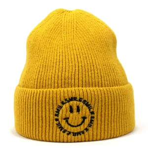 Close-up of yellow knitted beanie featuring detailed smile embroidery and soft wool texture