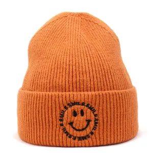 Close-up of bright orange knit beanie showing detailed texture and smile embroidery