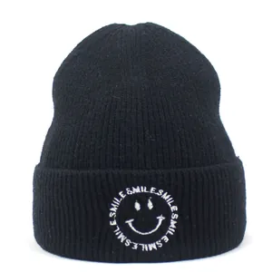 Close-up of black ribbed knit beanie featuring white Smile embroidery and letter logo