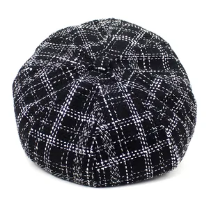 Detailed close-up of vintage black and white plaid tweed fabric texture on a newsboy cap