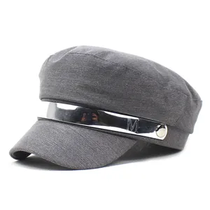 Detail of grey army cap featuring a silver metal band with M engraving and side buttons