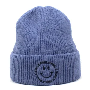 Detail of blue ribbed knit beanie with black smile embroidery and smile text pattern