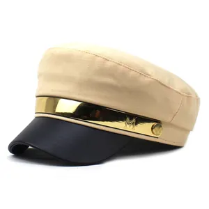 Détail de casquette militaire beige avec visière en cuir noir et barre métal dorée M