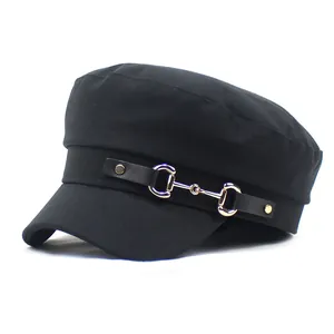 Detail of a black navy cap featuring a decorative gold horsebit metal buckle and strap