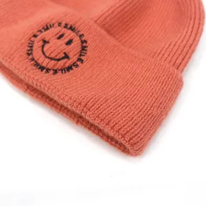 Orange knit beanie with smile embroidery and thick ribbed texture for winter warmth