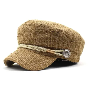 Detail of brown tweed newsboy hat with gold woven rope and lion embossed metal button