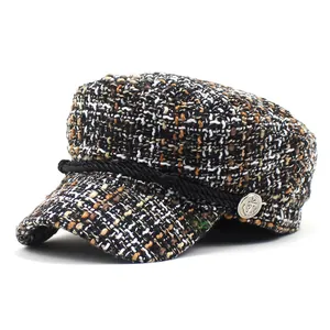 Detail of tweed navy cap showing woven texture, braided rope, and anchor embossed button