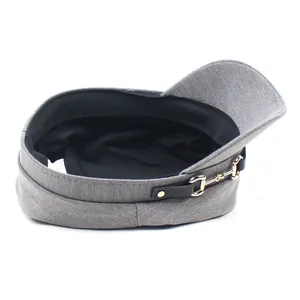 Detail view of grey newsboy cap showing twill fabric texture and golden horsebit accent