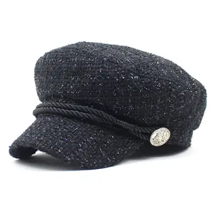 Detail of tweed newsboy cap showing woven texture, braided rope, and silver metal button