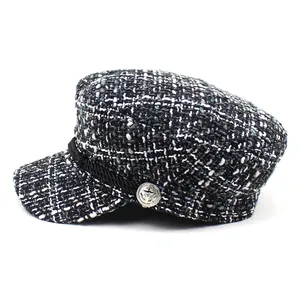 Detail view of tweed newsboy cap fabric texture and silver anchor button decoration