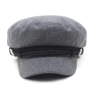 Detail of grey newsboy cap with black braided rope and silver metallic buttons
