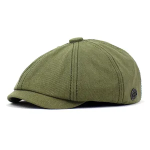 Detailopname van groene katoenen newsboy cap met decoratieve zijbadge en knop op de bovenkant
