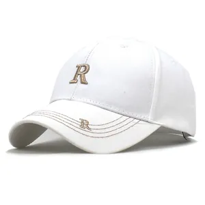Detalle del bordado de letra R en caqui y costuras decorativas en gorra blanca