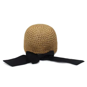 Dettaglio cappello di paglia intrecciato a mano con fiocco in nastro nero e trama