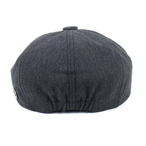 Detail van donkergrijze vintage baret met twill textuur en metalen zij-embleem